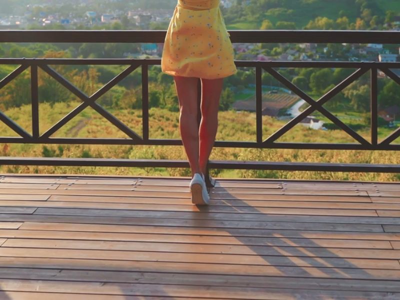devojka u žutoj suknjici i belim patikama uživa u pogledu sa vidikovca