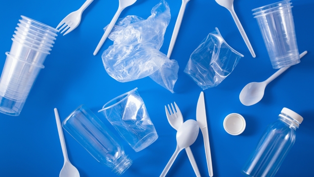 Plastični pribor, čaše, flaše i kese za jednokratnu upotrebu razbacani po plavoj podlozi.