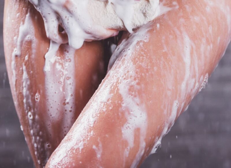 prikaz devojke pod tušem koja spira penu sa svojih nogu