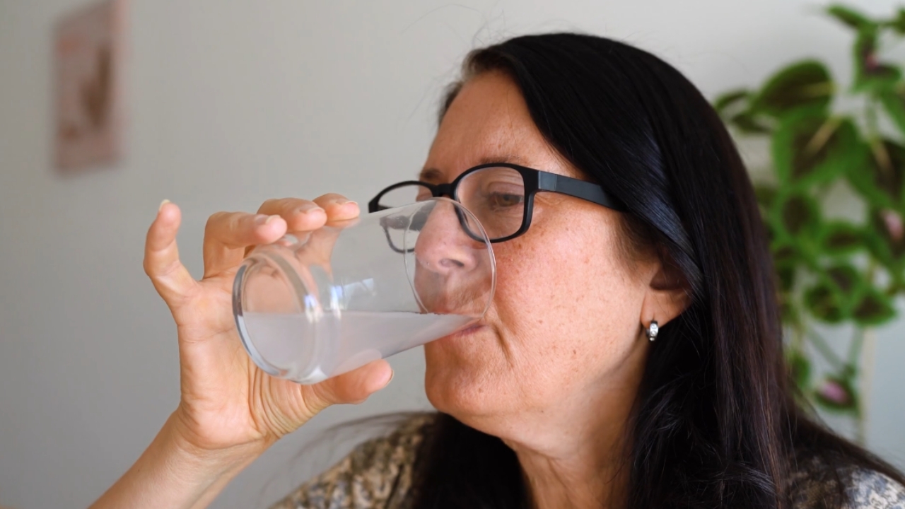 Žena pije kolagen rastvoren u čaši vode.